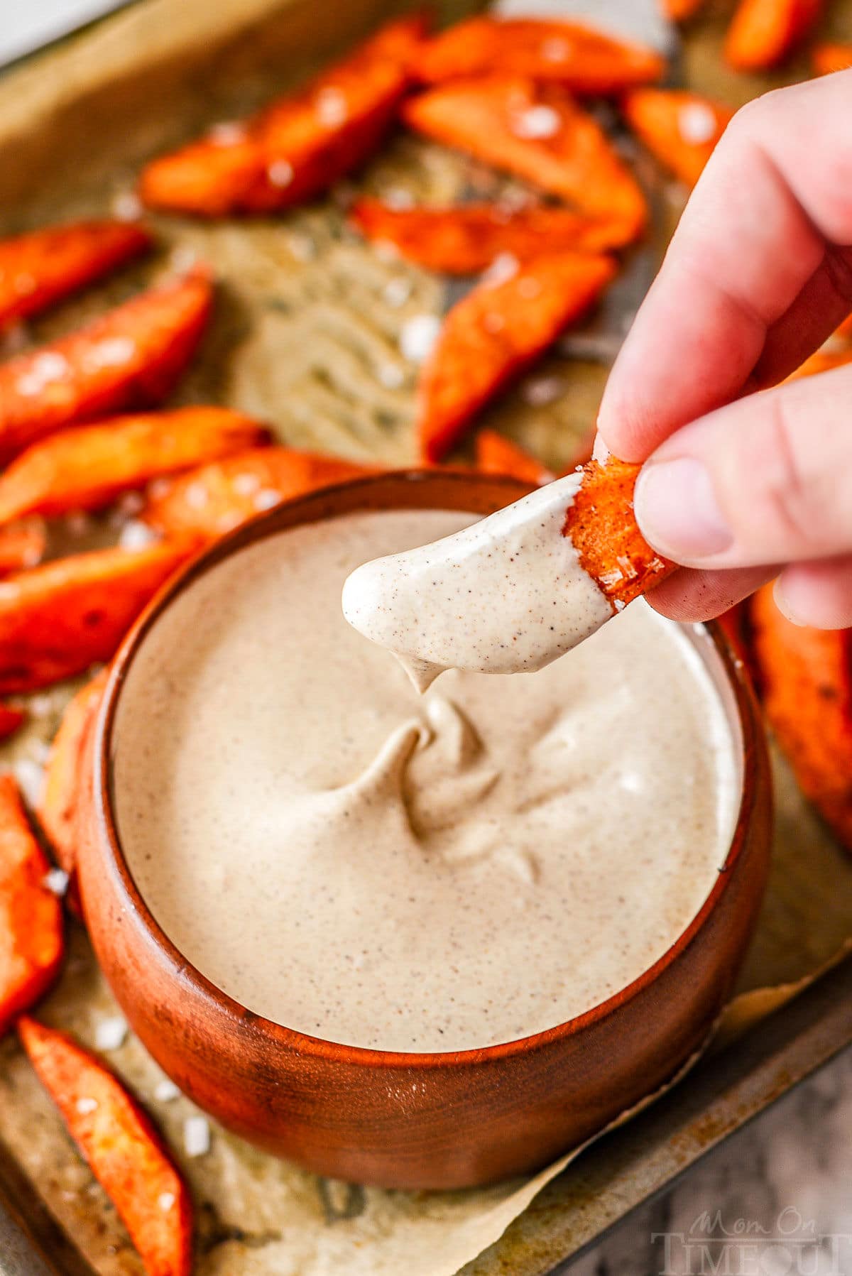 Sweet potato wedges being dipped into bowl of marshmallow dipping sauce.