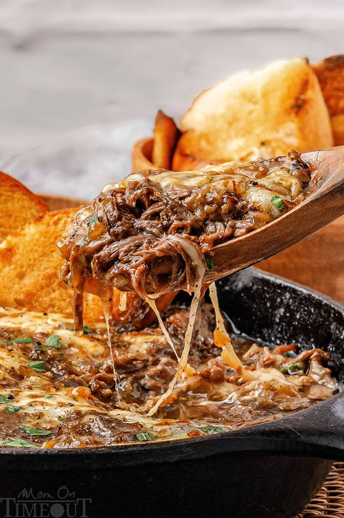 French onion soup pot roast being lifted out of the pan after the roast has been shredded.