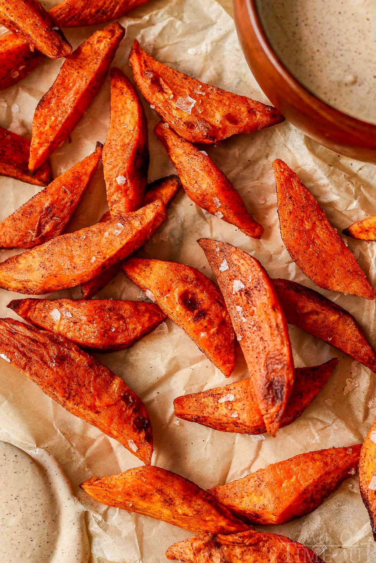 Overhead shot of sweet potato wedges on baking sheet lined with parchment. Sea salt has been sprinkled on top of the wedges.