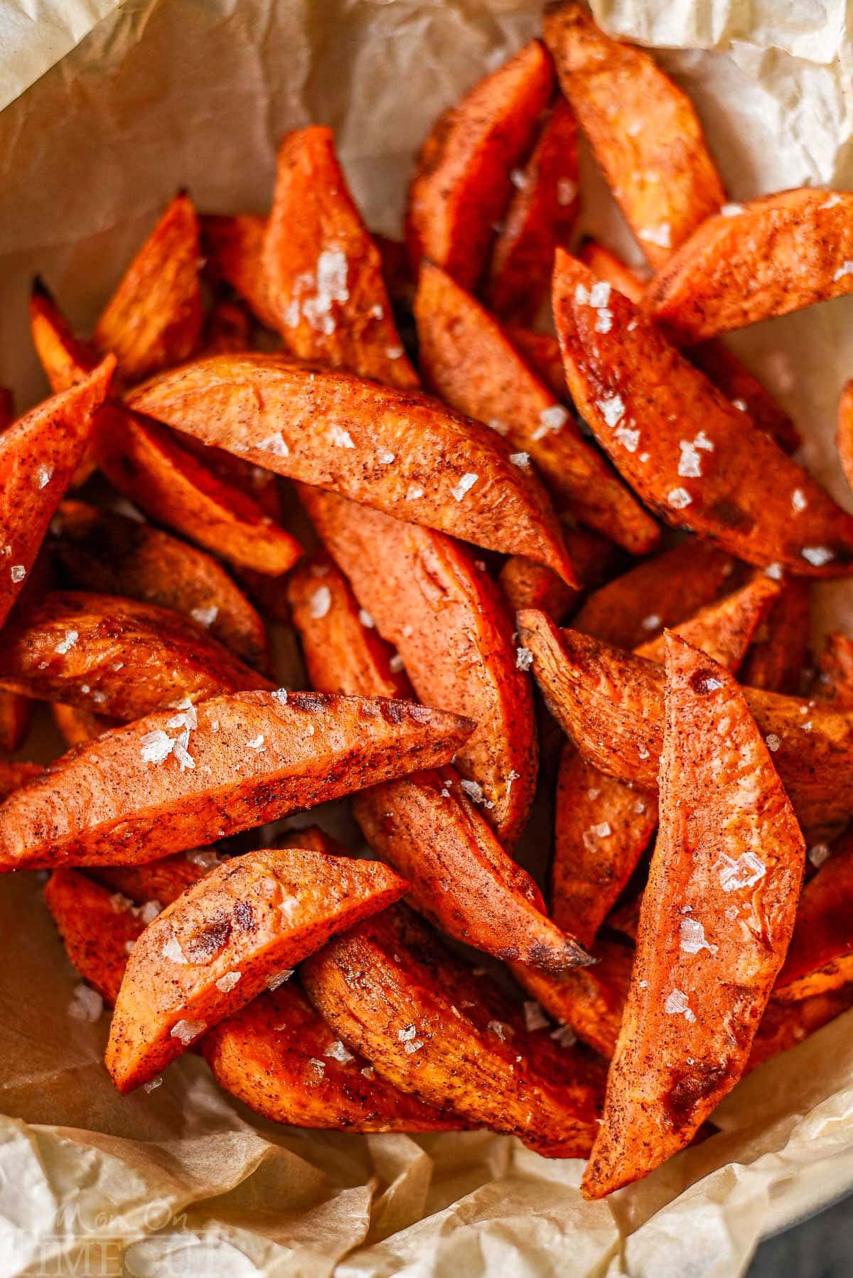Close up shot of sweet potato wedges sprinkled with flaky sea salt.