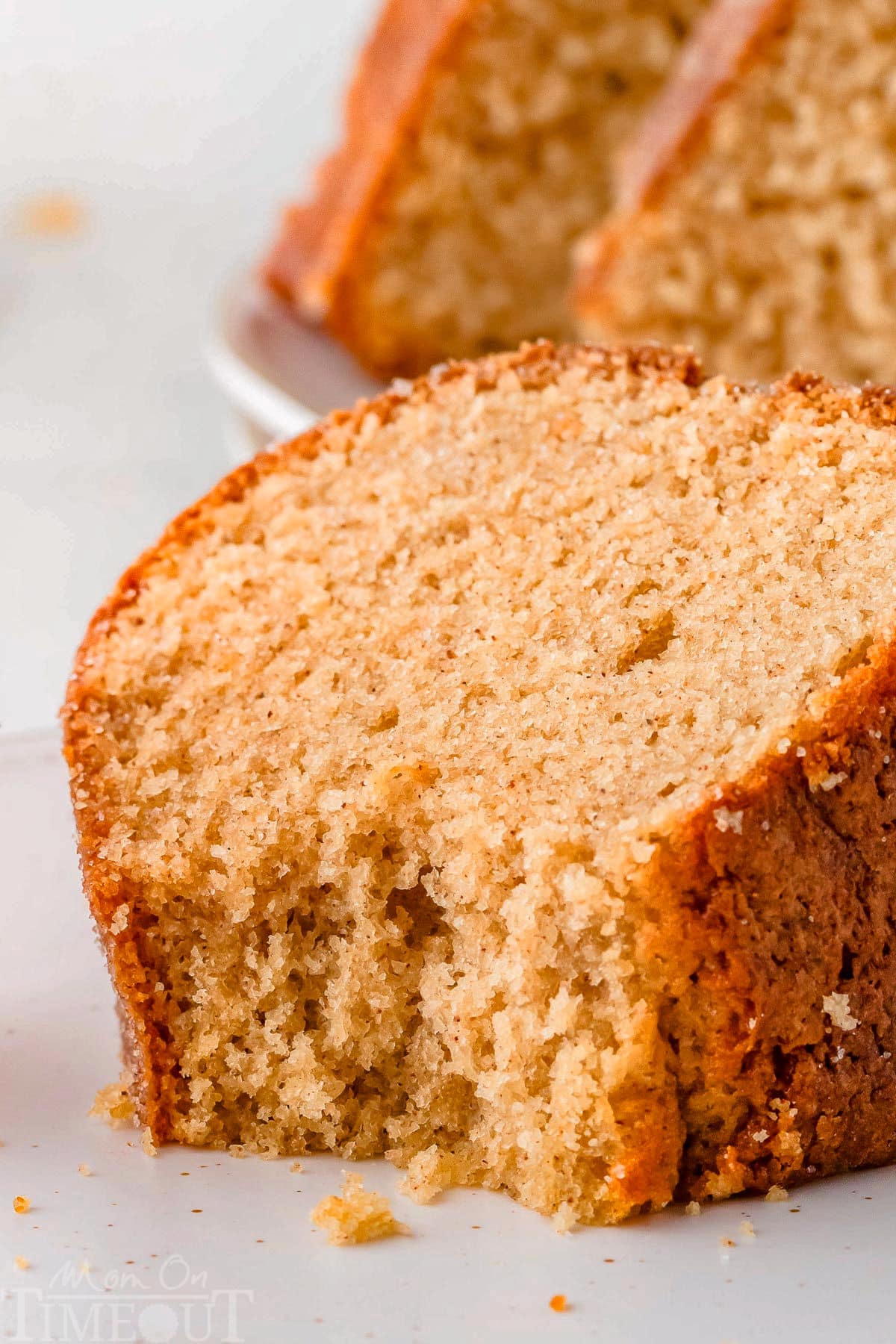 Piece of apple cider bundt cake on plate with bite taken out of it.