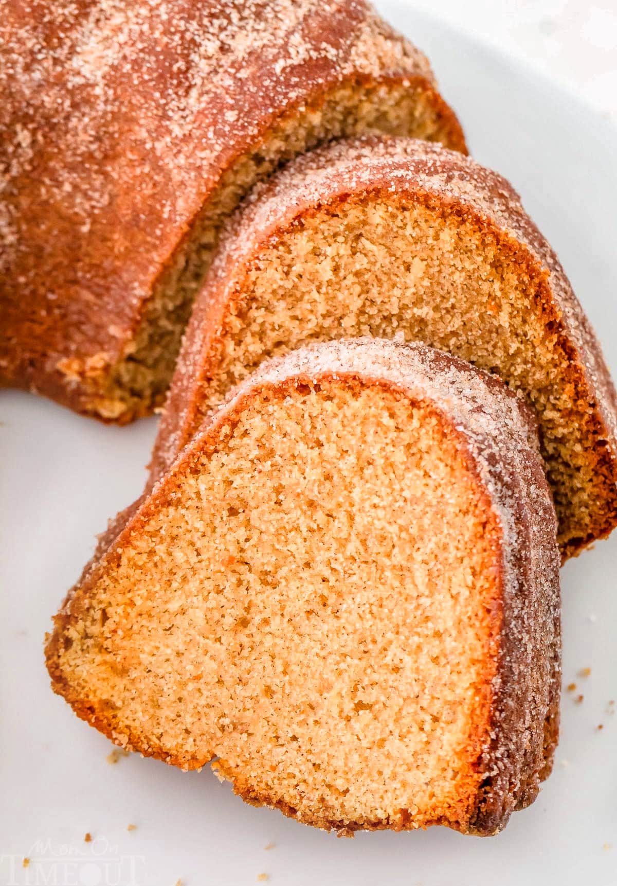 Angled down view of two pieces of apple cider bundt cake cut off the bundt and sitting on a white cake stand.