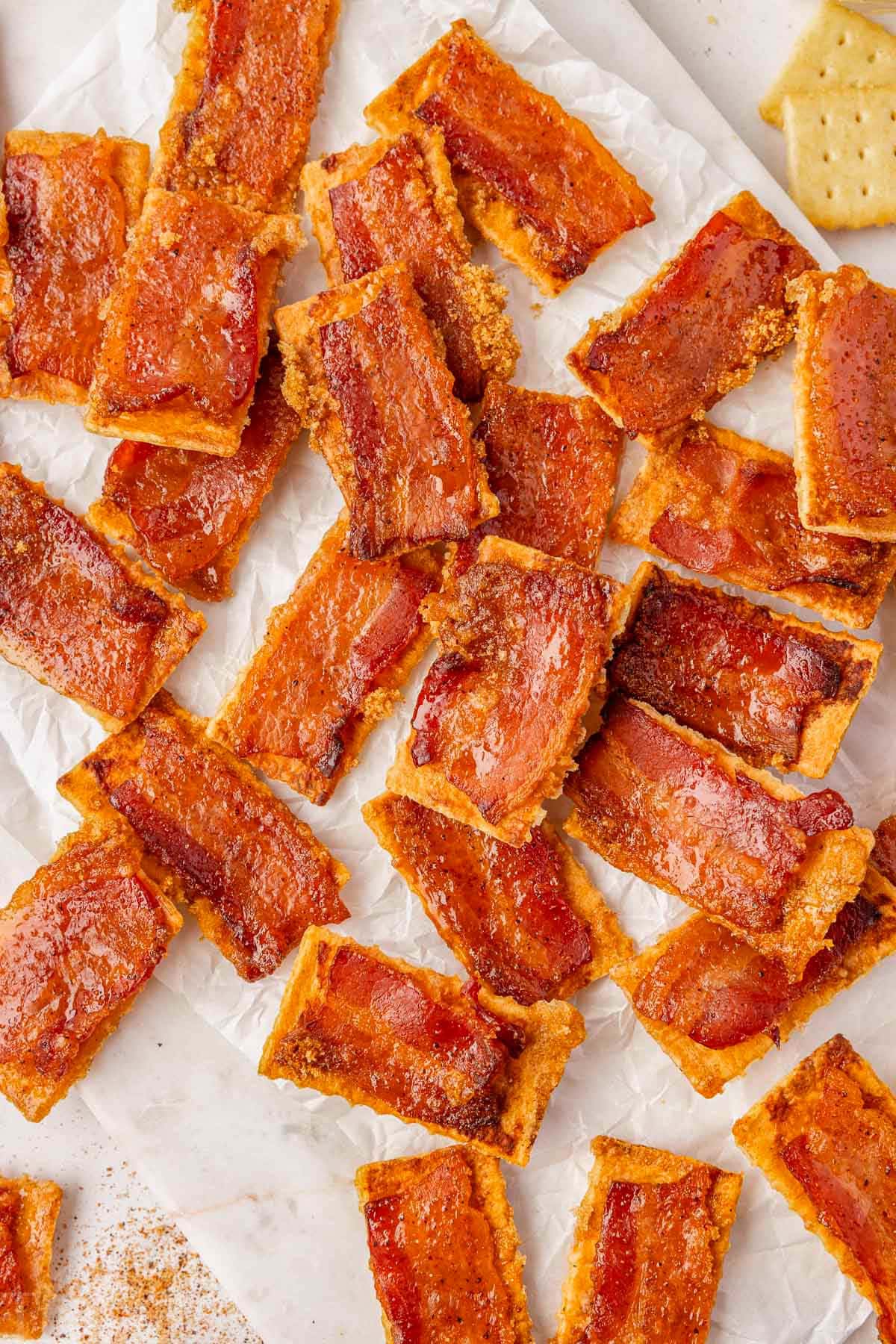Overhead shot of bacon brown sugar crackers on white parchment ready to be served and enjoyed.