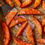 Top down look at roasted sweet potato wedges on parchment lined baking sheet.