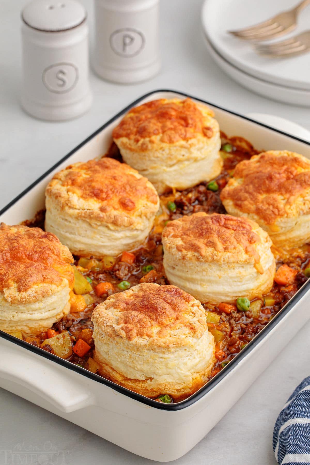 Beef pot pie topped with biscuits in white casserole dish ready to be served. Six biscuits on top.