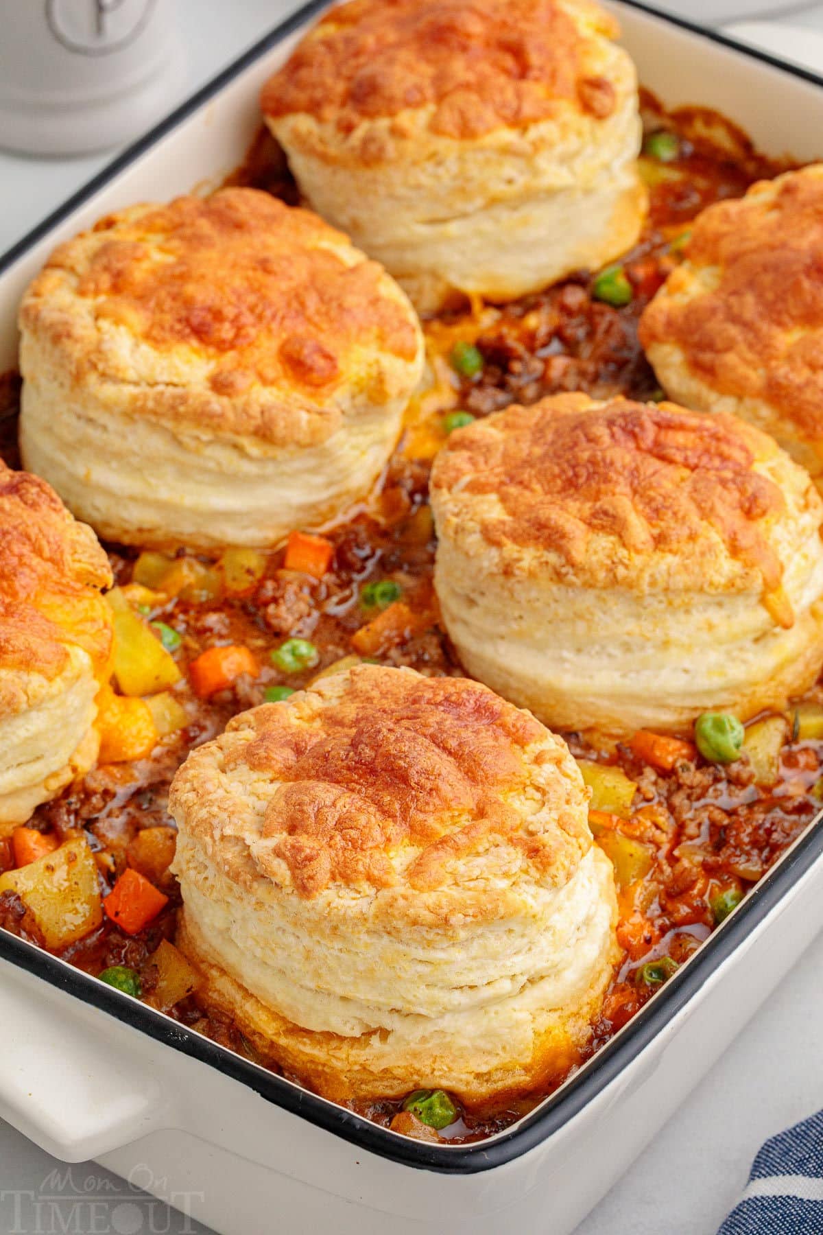 Beef pot pie topped with biscuits in white casserole dish ready to be served. Six biscuits on top.