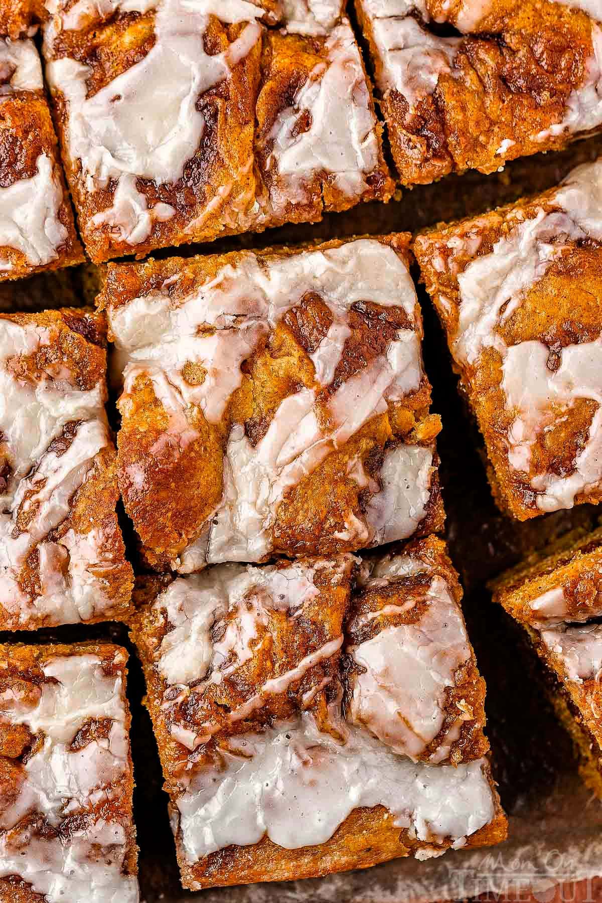 Overhead shot of pumpkin cinnamon focaccia cut into squares drizzled with glaze.