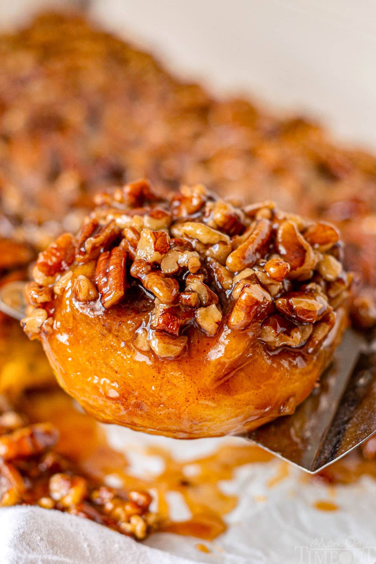 Pumpkin sticky bun being lifted off of cutting board and ready to be enjoyed.