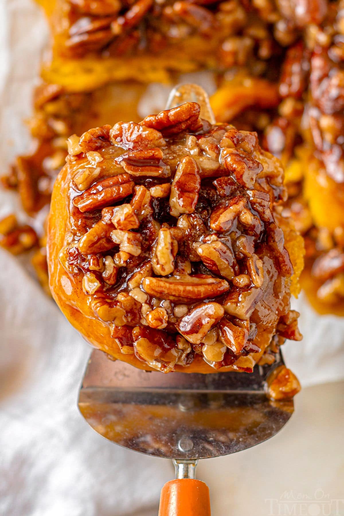 Pumpkin sticky bun being lifted off of cutting board and ready to be enjoyed.