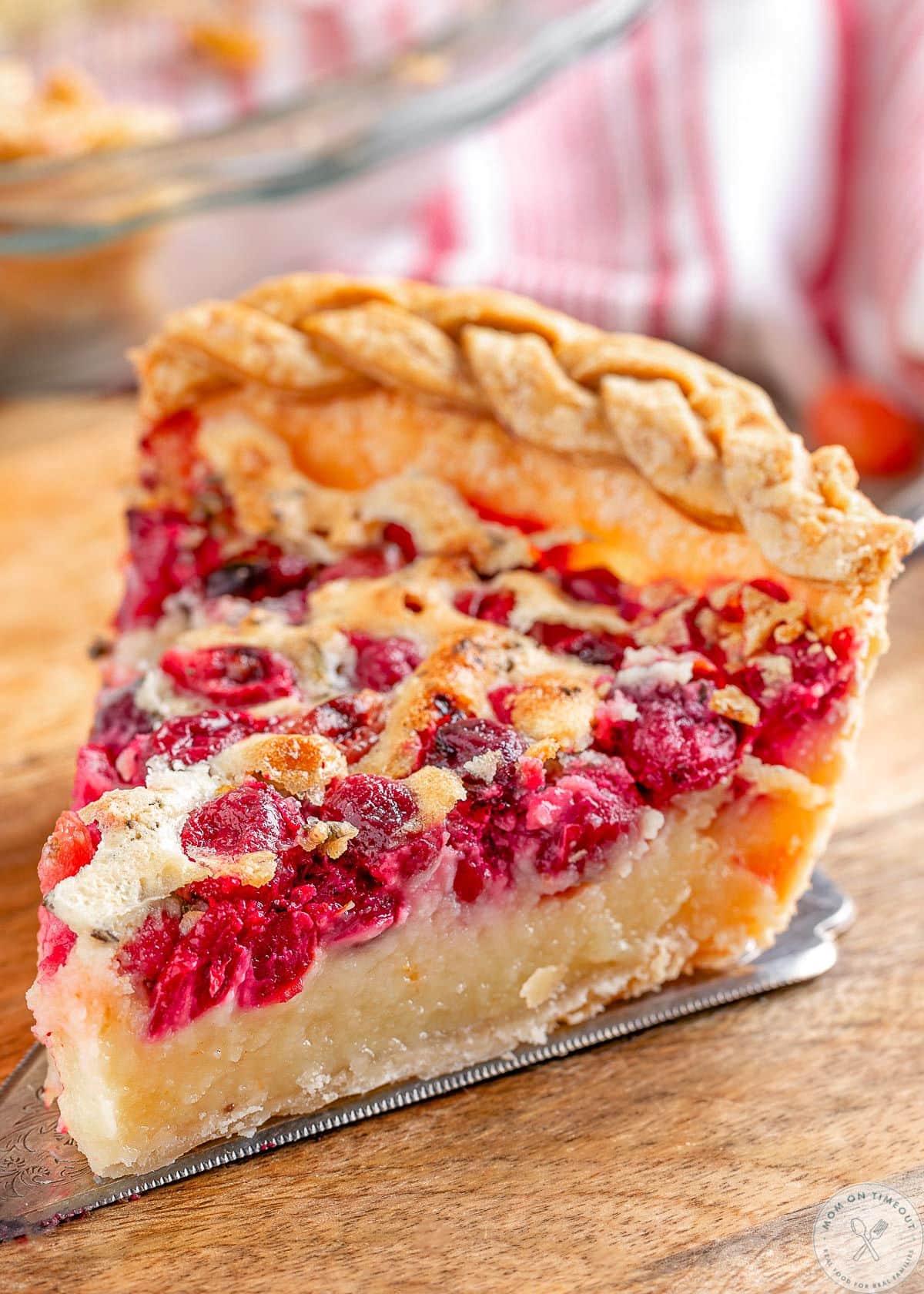 Slice of cranberry custard pie sitting on wood cutting board.