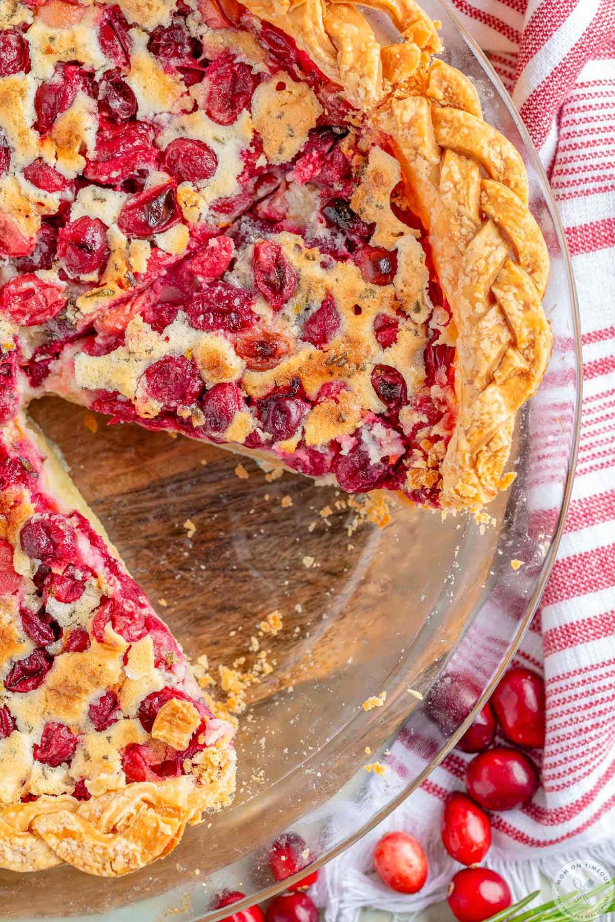 Overhead shot of cranberry pie in pie plate with one piece removed.