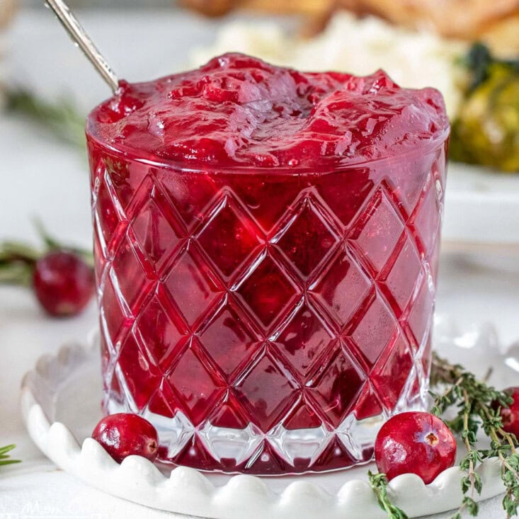 Cranberry sauce in glass jar on white plate.