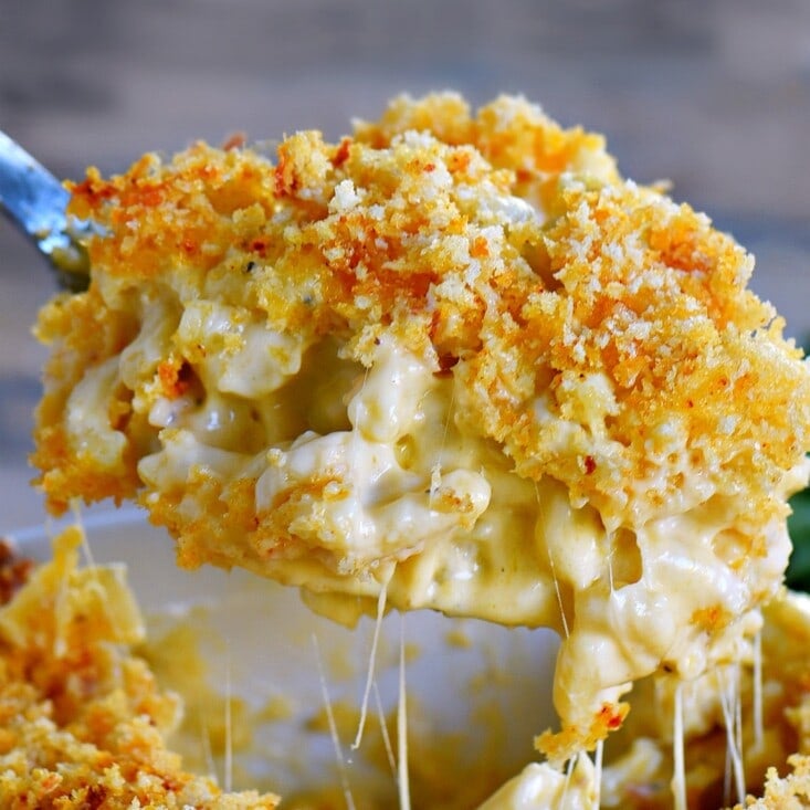 Creamy homemade mac and cheese recipe being scooped out of baking dish.