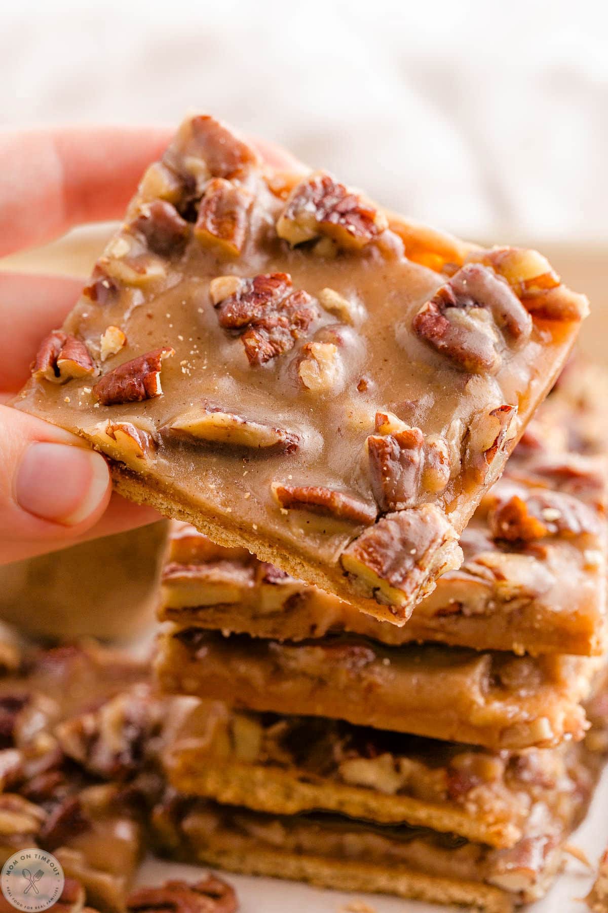 Handing picking up a piece of pecan pie bark of a stack of bark.