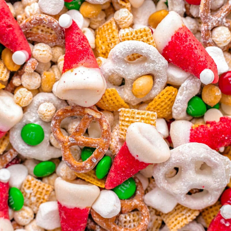 Close up shot of santa hat christmas snack mix including cereal, pretzels and candy.