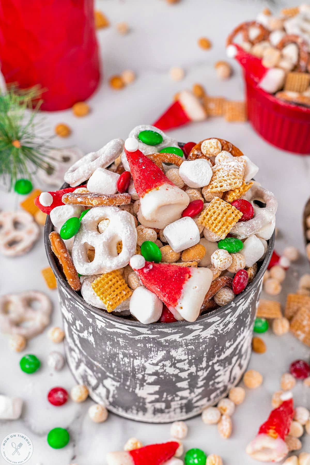 Metal bucket filled with santas snack mix including cereals, pretzels and candy. 