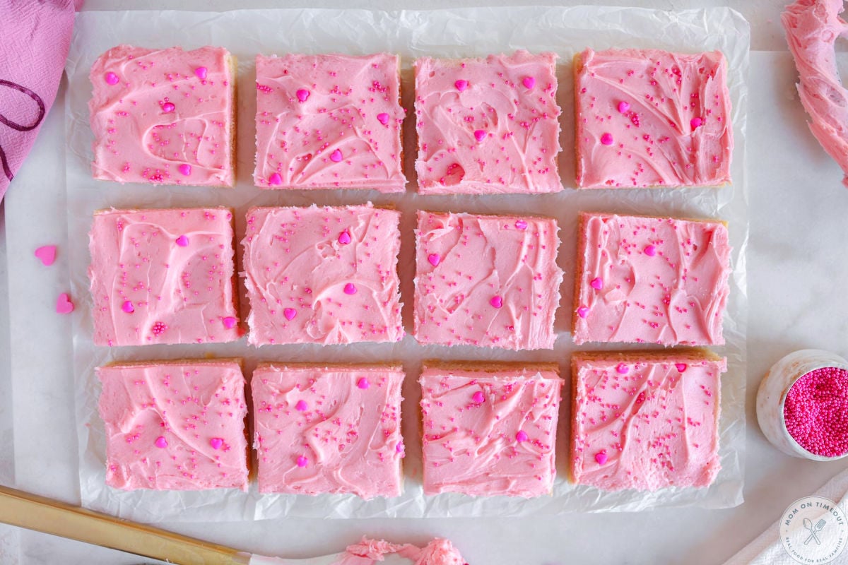 Wide shot of sugar cookie bars cut into squares on parchment paper.