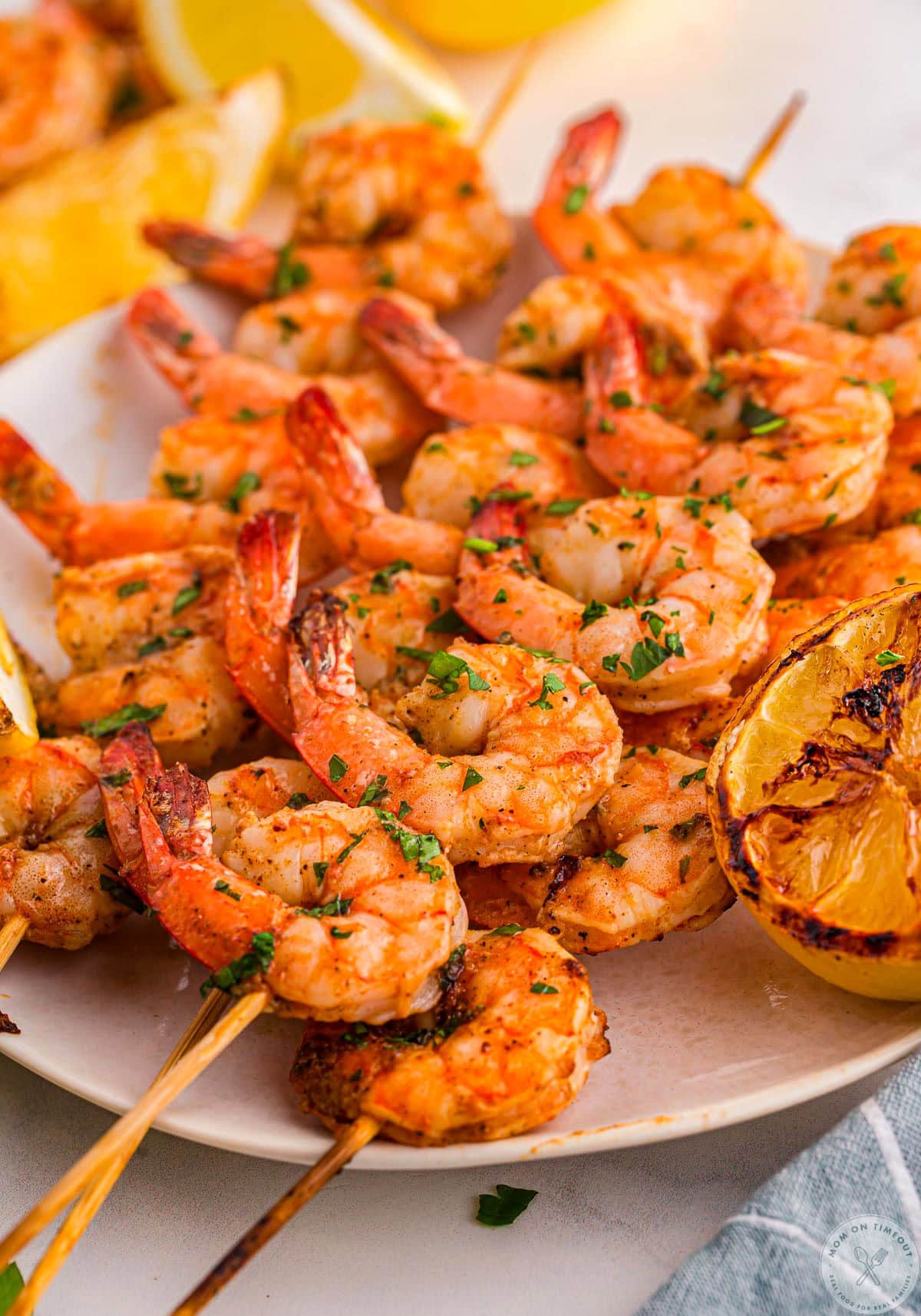 Plate topped with cajun shrimp on skewers ready to be enjoyed. Lemon wedges can be seen in the background.