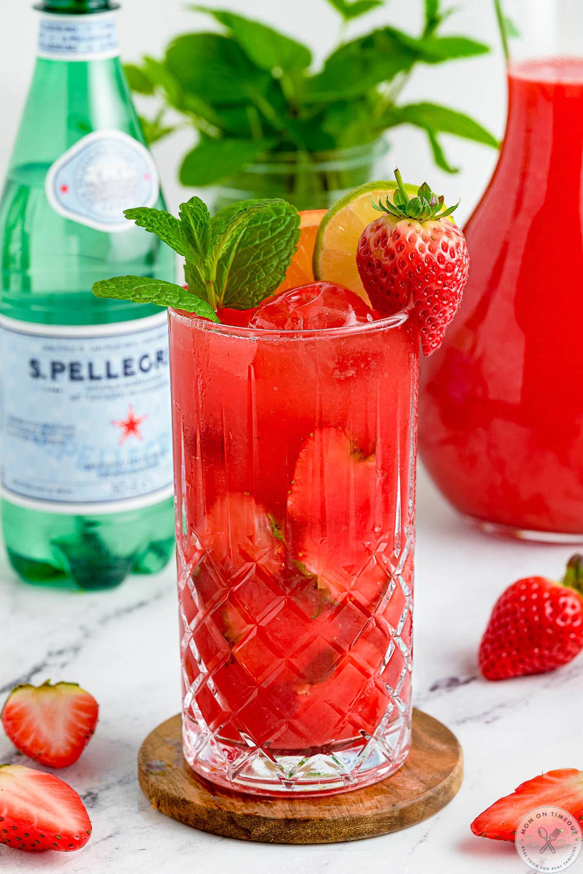 Strawberry Mojito mocktail with a glass of sparkling water in the background.