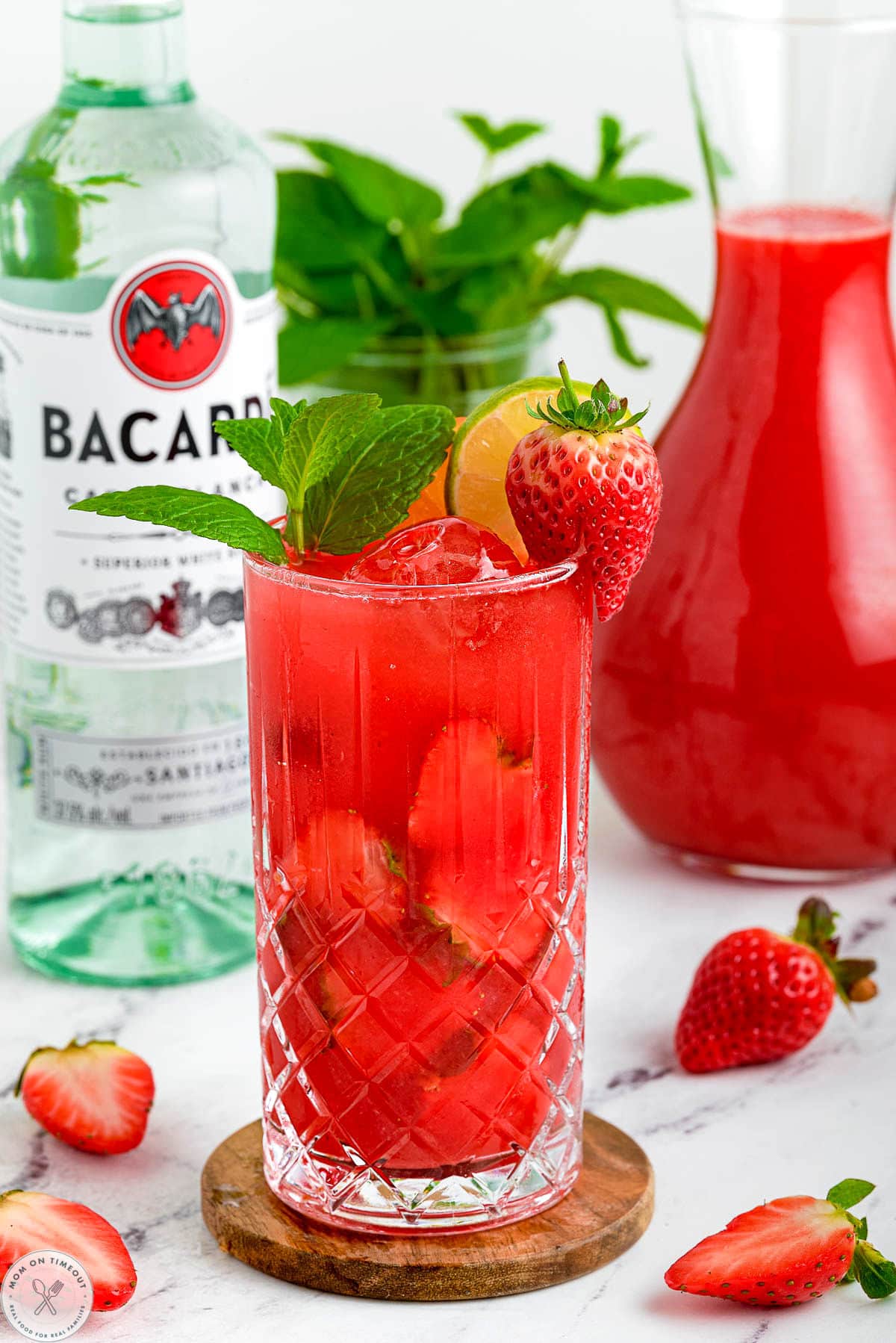 Strawberry Mojito with a bottle of rum in the background.