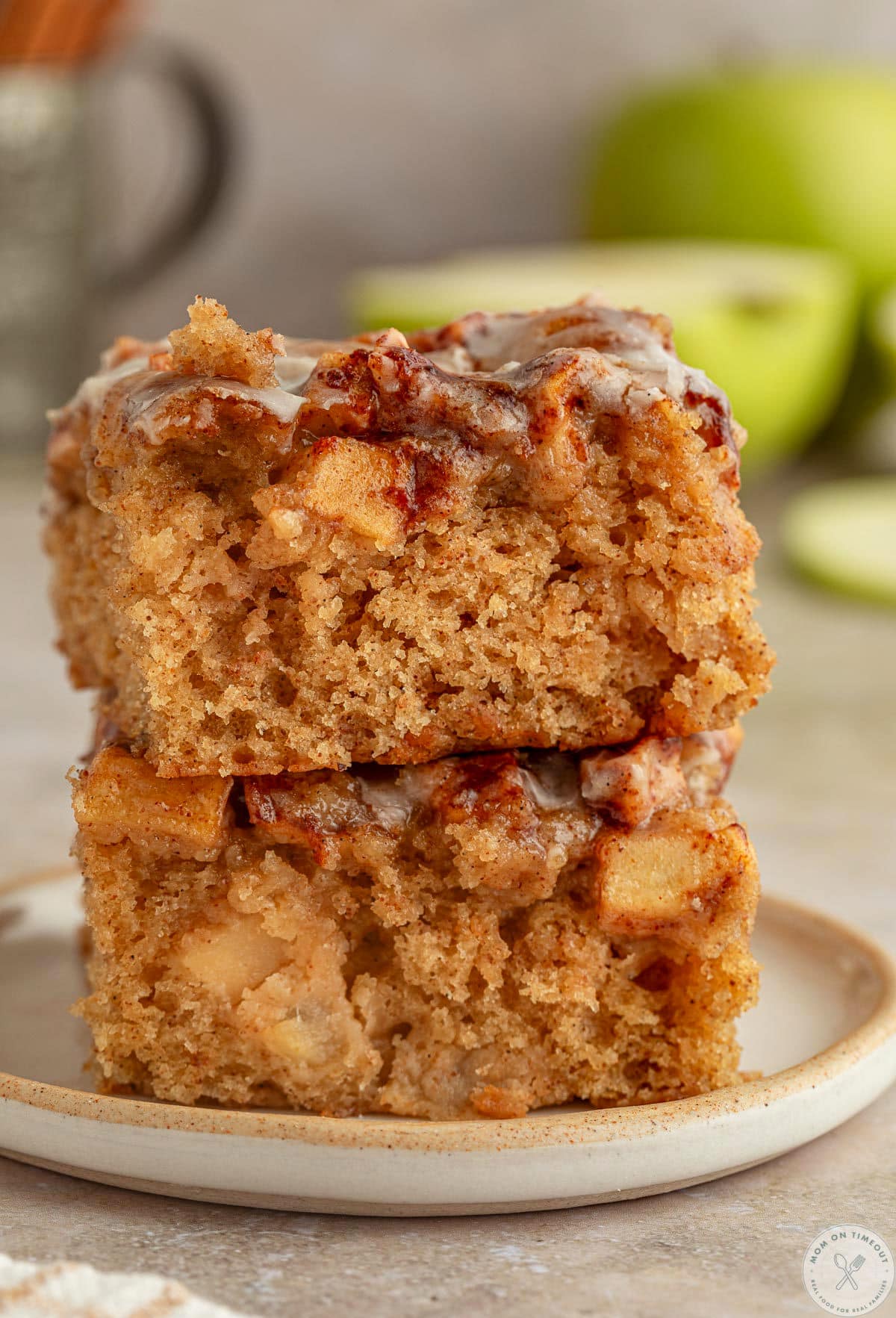 Two pieces of apple fritter cake recipe stacked on a small round plate.