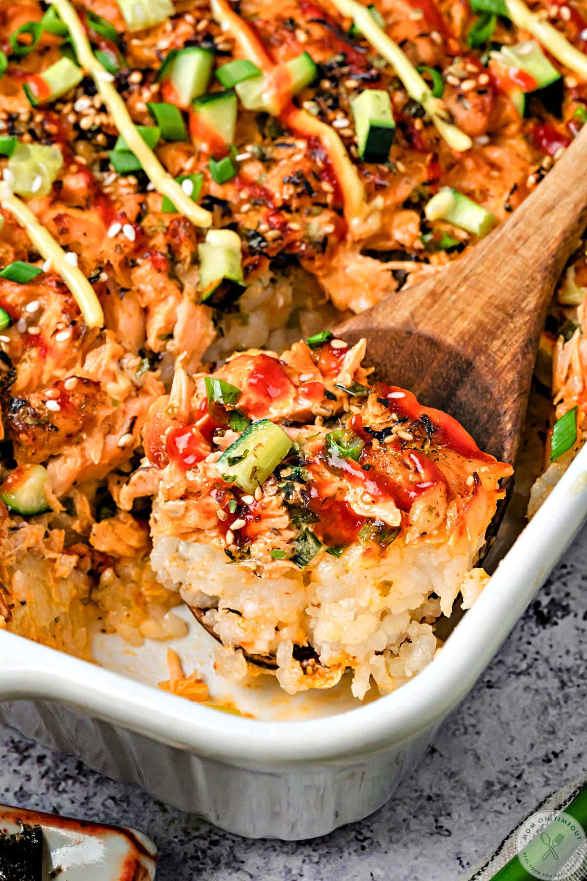 Angled overhead shot of a scoop of baked sushi being removed from the baking dish.