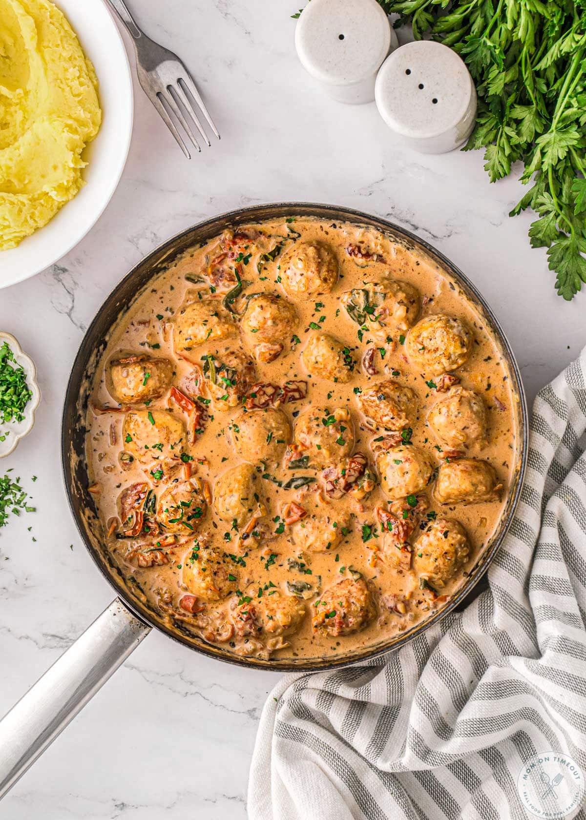 Marry me chicken meatballs in skillet with creamy sun dried tomato and Parmesan sauce. Mashed potatoes in bowl to the side.