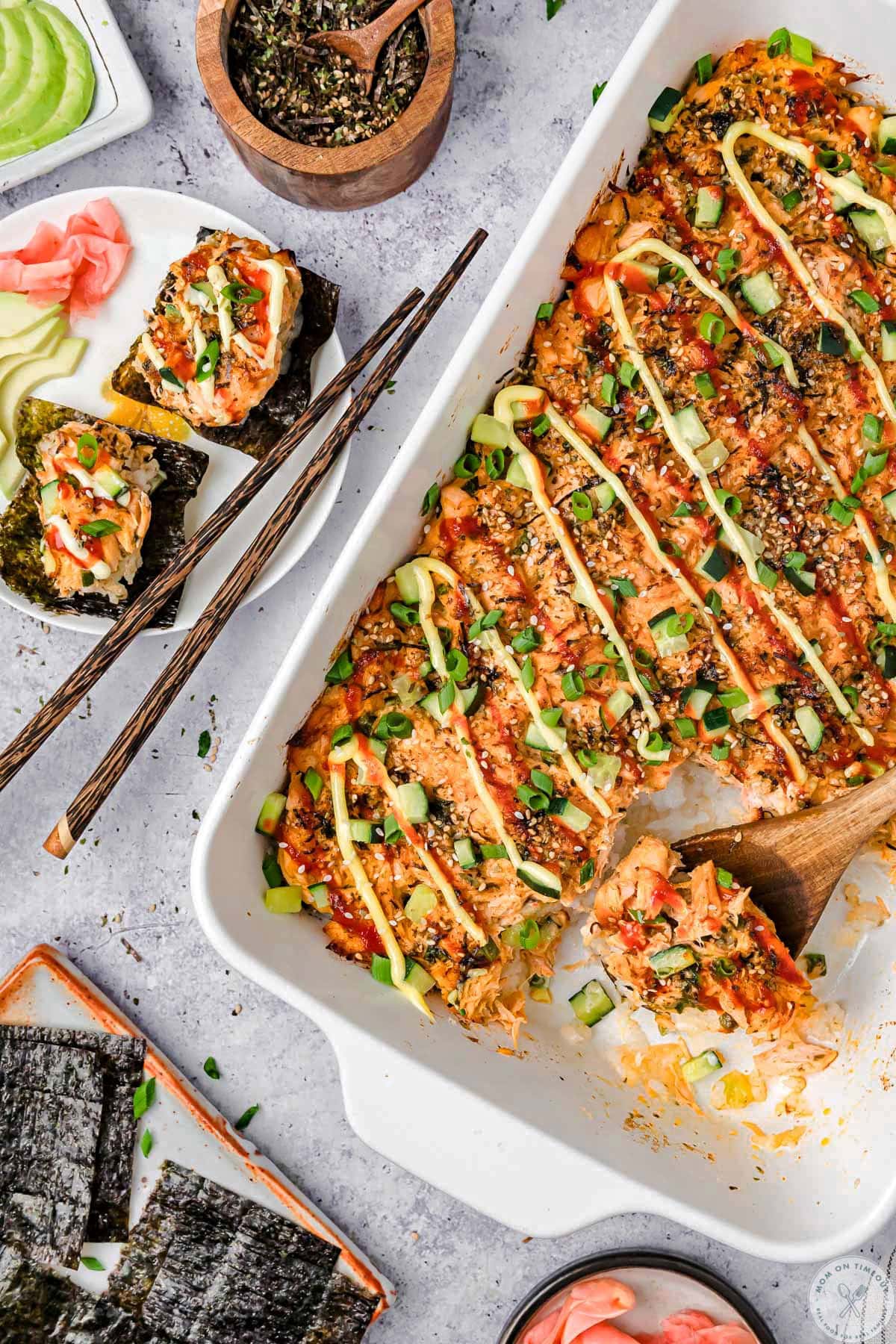 Overhead shot of sushi bake recipe salmon in baking dish and a serving plate with nori.